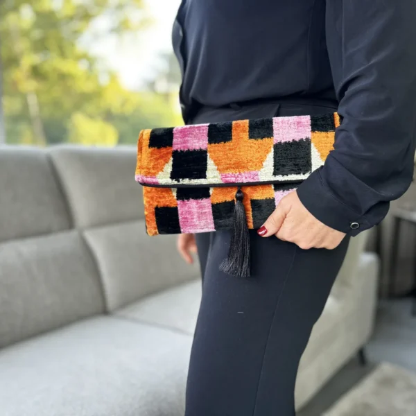 Un jeu de couleurs, un motif qui accroche le regard et beaucoup de caractère. La pochette graphique femme Santorin associe rose, orange, noir et écru dans un superbe velours de soie Ikat. Confectionnée artisanalement, elle offre un toucher doux et de jolis reflets qui évoluent avec la lumière. Son format accueille facilement téléphone, portefeuille, clés et petits essentiels.
