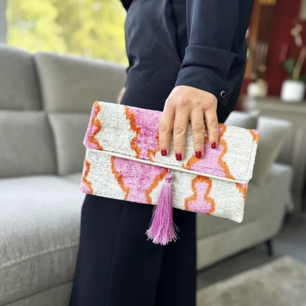 Un concentré de soleil à emporter partout.  La pochette rose orange femme Positano mêle rose vibrant, orange et écru dans un superbe velours de soie Ikat au caractère unique. Confectionnée artisanalement en velours 100 % soie, elle offre un toucher doux et de jolis reflets. Son format accueille facilement téléphone, portefeuille, clés et maquillage.