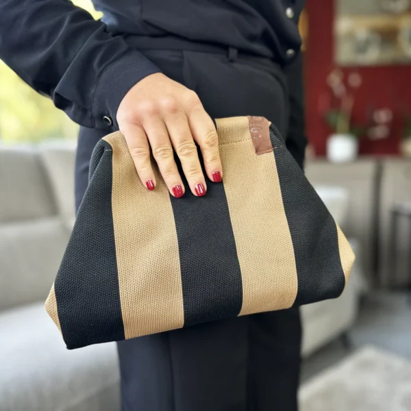 Graphique, chic et ultra-facile à porter, cette pochette moka femme joue le contraste entre noir et camel pour donner du caractère à vos looks. Son format compact accueille téléphone, maquillage et petits essentiels sans vous encombrer. À porter à la main en journée ou en soirée, elle peut également devenir une jolie trousse à glisser dans votre grand sac.